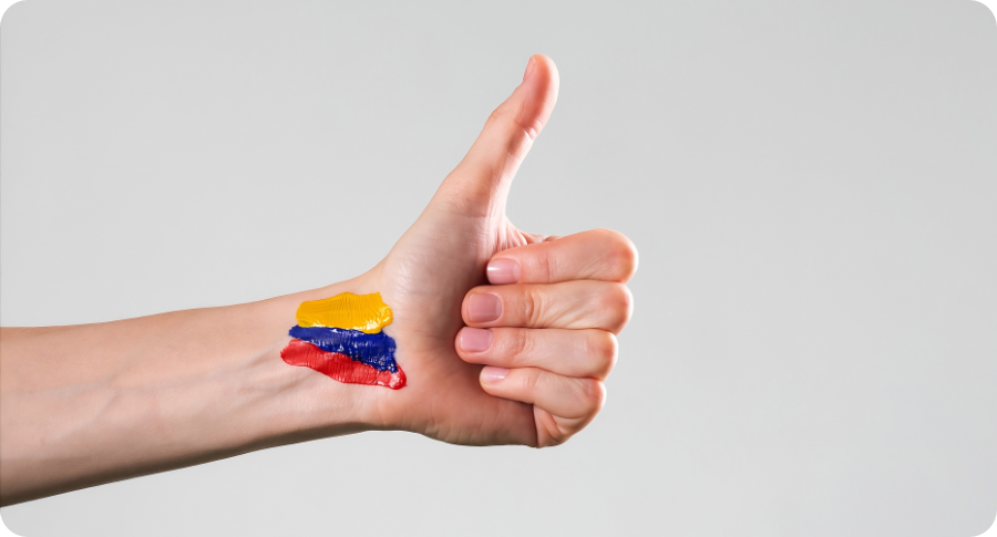 Mano con pulgar hacia arriba y la bandera de Colombia pintada en el antebrazo